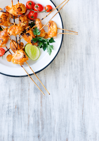 Healthy chicken kebabs served with tomatoes lime and coriander on a rustic enamel plate, copy spaceの写真素材