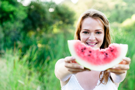 Happy carefree summer girl in outdoor park field with healthy refreshing watermelon fruitの写真素材