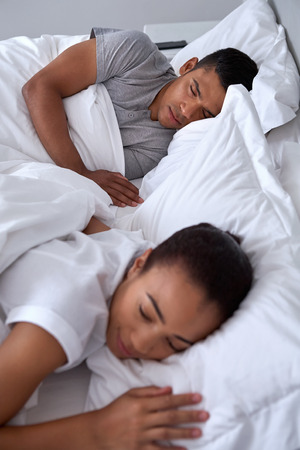peaceful young couple sleeping comfortably in bed at homeの写真素材