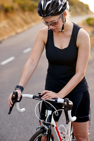 woman fitness trainer cyclist setting timer on bicycleの写真素材