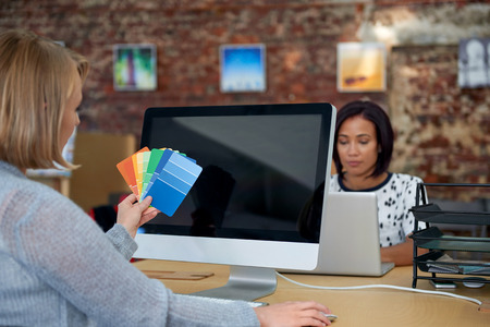 creative graphic designer woman comparing colour swatches in open plan agencyの写真素材