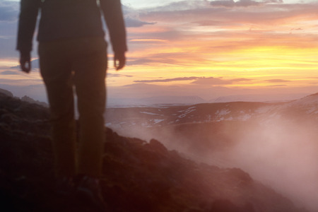 Iceland geothermal lava fields with steam from hot ground with tourist walking on dangerous unstable cliffの写真素材