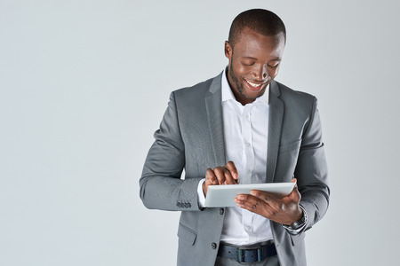 Candid portrait of positive friendly black  professional businessman with touchscreen tablet device isolated in studioの写真素材