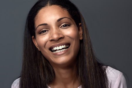 Natural smiling portrait of a hispanic latino indian asian woman against dark grey backgroundの写真素材