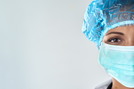 Close up of confident female surgeon in mask getting ready for medical procedure surgeryの写真素材