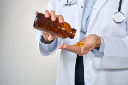 Anonymous female medical practitioner holding up bottle of pills, health supplement vitamins prescription drugsの写真素材