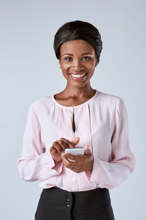 beautiful black african woman texting on her mobile cell phone smartphone in corporate office attireの写真素材