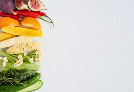 Colourful gradient of healthy fresh fruit and vegetables, fig chilli orange mango pineapple celery rosemary cucumber cauliflower, artistic spectrumの写真素材