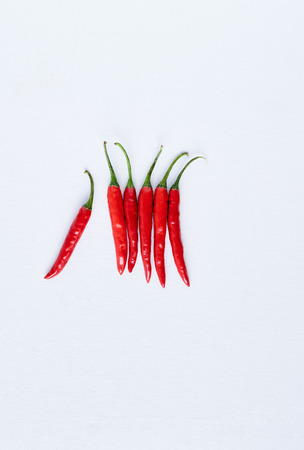 Food background of bunch of fresh hot spicy bird's eye chillis on white background, with one sticking out odd one out, plenty of copy spaceの写真素材