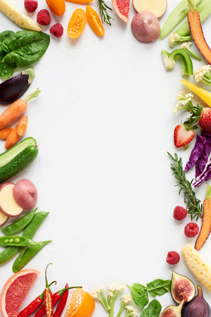 Food background border frame flatlay overhead of colorful fresh produce raw vegetables, carrot chilli cucumber purple cabbage spinach rosemary herb, plenty of copy-space in middleの写真素材