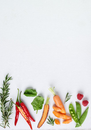Organic fruit and vegetables herbs on white background, rosemary, chilli, spinach, heirloom carrots, raspberry, plenty of copy spaceの写真素材