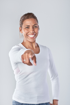 Portrait of indian woman choosing, hand pointing into camera in studioの写真素材