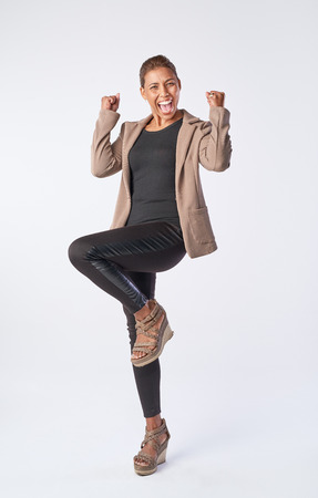 Full length portrait of mixed race woman celebrating in joy isolated on greyの写真素材