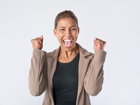 Real woman celebrating happy positive expression in studio isolated on greyの写真素材