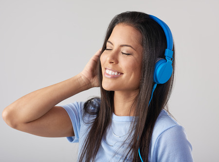 Headshot of hispanic woman enjoying listening to music with large headphones in studioの写真素材