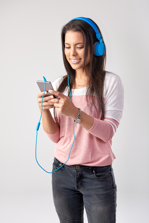 Mixed race woman with headphones listening to music and creating a playlist on her phoneの写真素材