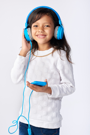 young girl playing her favorite song on headphones isolated in studioの写真素材