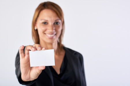 Woman business card showing towards camera isolated in studioの写真素材