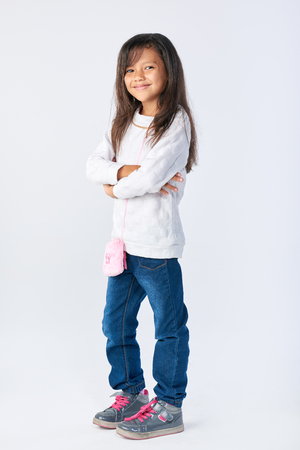cute adorable girl posing for picture with arms crossed isolated in studioの写真素材