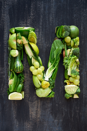 complete collection of alphabet letters made from healthy green fruit and vegetables on rustic distressed texture, overhead flat layの写真素材