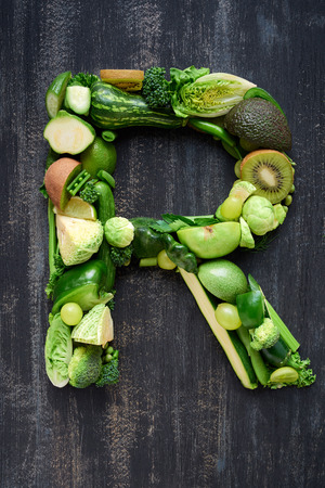 overhead flat lay display of green fruit and vegetables arranged in alphabet letter shapes, for design websites postersの写真素材