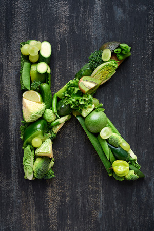 overhead flat lay display of green fruit and vegetables arranged in alphabet letter shapes, for design websites postersの写真素材