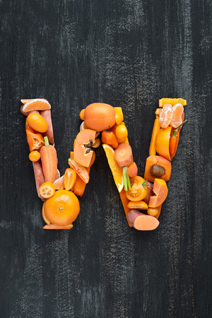 complete collection of alphabet letters made from healthy orange fruit and vegetables on rustic distressed texture, overhead flat layの写真素材