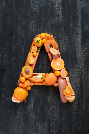 complete collection of alphabet letters made from healthy orange fruit and vegetables on rustic distressed texture, overhead flat layの写真素材