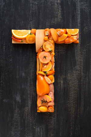 Flat lay series of healthy orange produce fruit and vegetables shaped into letters of alphabet, design element poster spelling layoutの写真素材