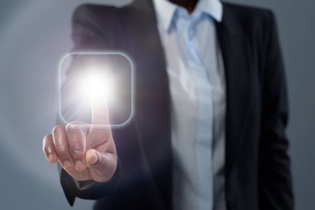 Anonymous african business woman touching a digital interface glowing buttonの写真素材