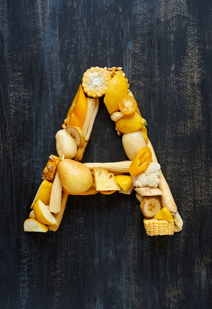 Variety of yellow toned fruit and vegetables shaped into letters for food related designの写真素材