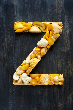 Variety of yellow toned fruit and vegetables shaped into letters for food related designの写真素材