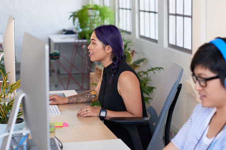 Asian women working at their desks in creative non conventional office filled with plantsの写真素材