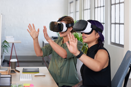 Asian woman showing her colleague her new project using virtual reality headsets, modern innovative architecture firmの写真素材
