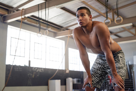 Portrait of shirtless man resting while training in industrial gymの写真素材