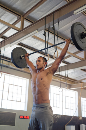 Strong muscular man lifting heavy weights training working ou shirtlessの写真素材