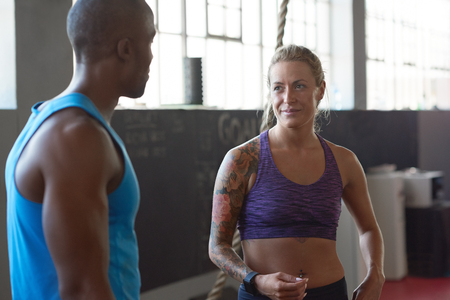 Fit lean man and healthy woman with tattoos talking in gym before crossfit class, exercise fitness conceptの写真素材