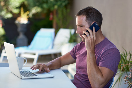 Man sitting on terrace and working on his laptop while on holiday vacation, freelancer lifestyle flexible mobile officeの写真素材