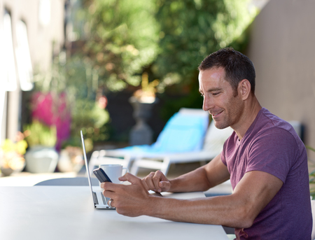 Man sitting on terrace and working on his laptop while on holiday vacation, freelancer lifestyle flexible mobile officeの写真素材