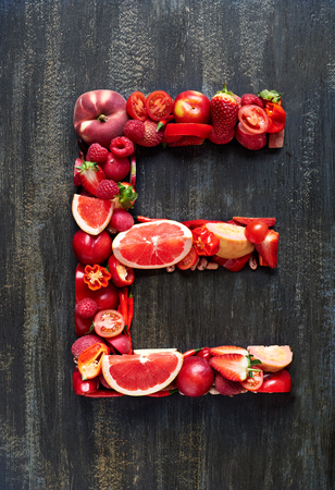 Complete flat lay collection of alphabet letters made from red fruit and vegetables on dark distressed background, overhead setの写真素材