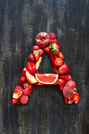 Complete flat lay collection of alphabet letters made from red fruit and vegetables on dark distressed background, overhead setの写真素材