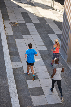 Group of fit healthy friends running under a bridge in urban cityの写真素材