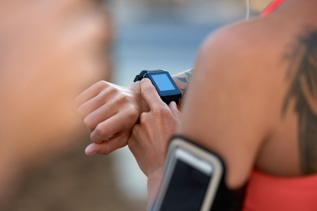 Anonymous woman with tattoos looking at her run exercise progress with wearable technology device in urban cityの写真素材