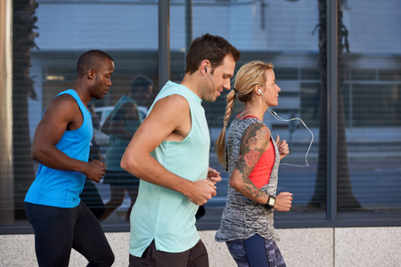 Diverse group of people exercising running jogging working out together in the city urban landscape, motion shotの写真素材