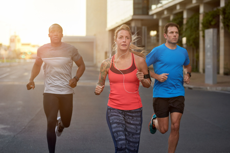 Diverse group of people exercising running jogging working out together in the city urban landscape, motion shotの写真素材