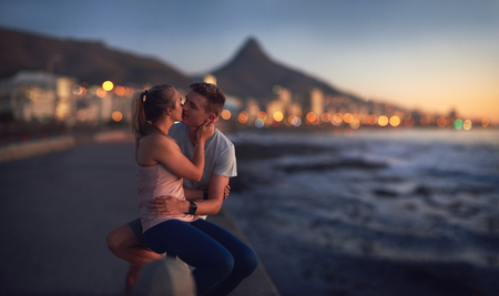 Affectionate couple kiss along the ocean at sunset, romantic holiday memoriesの写真素材