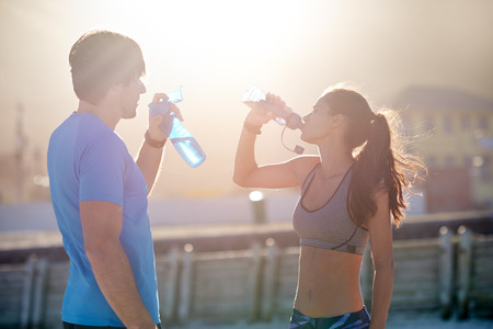 Active fitness couple hydrating drinking water in between their exercises  after their runの写真素材