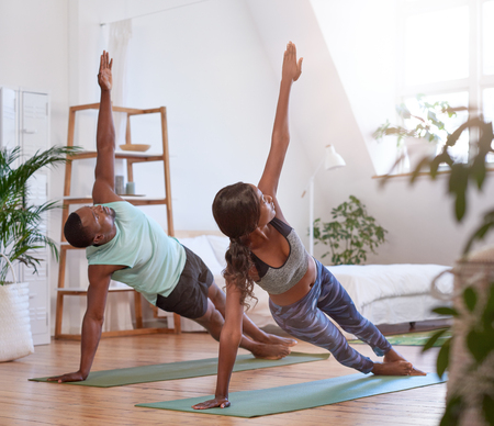 Young attractive couple practising yoga stretching workout at home, healthy lifestyle body careの写真素材