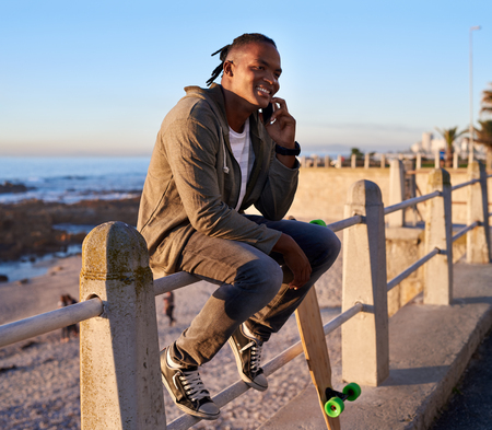 Smiling man having a conversation on phone device, using technology outdoorsの写真素材