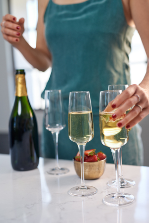 Anonymous woman passing glass of champagne, holiday festive season celebrationの写真素材